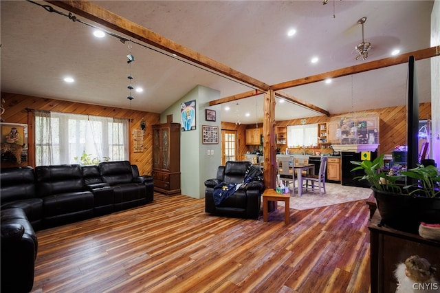 living room with wood walls, lofted ceiling with beams, and hardwood / wood-style flooring