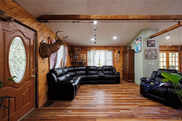 living room with wood-type flooring, wooden walls, and vaulted ceiling