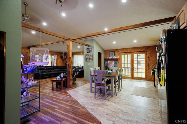 dining room with wooden walls, french doors, vaulted ceiling, light hardwood / wood-style floors, and ceiling fan