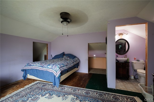 bedroom featuring connected bathroom, vaulted ceiling, ceiling fan, and sink