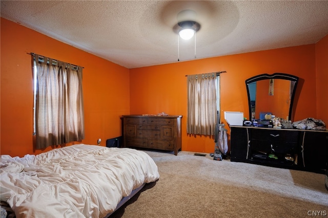 bedroom featuring light colored carpet, ceiling fan, multiple windows, and a textured ceiling