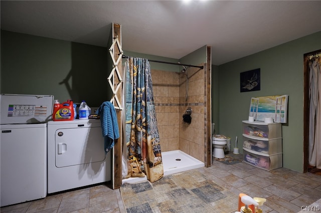 bathroom with tile flooring, independent washer and dryer, a tile shower, and toilet