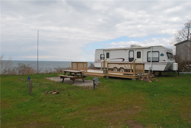 rear view of house featuring a yard and a deck with water view