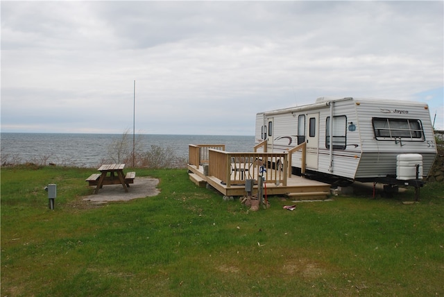 view of dock featuring a deck with water view and a yard