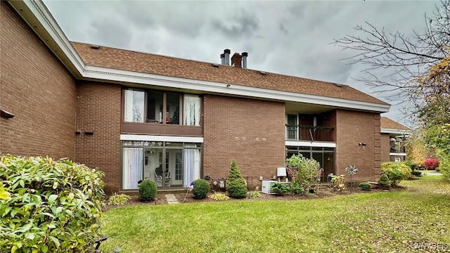 rear view of house with a balcony and a lawn