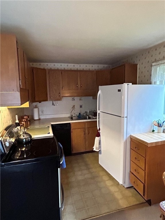 kitchen with electric range oven, sink, black dishwasher, and white refrigerator