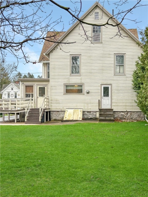 rear view of house featuring a wooden deck and a yard