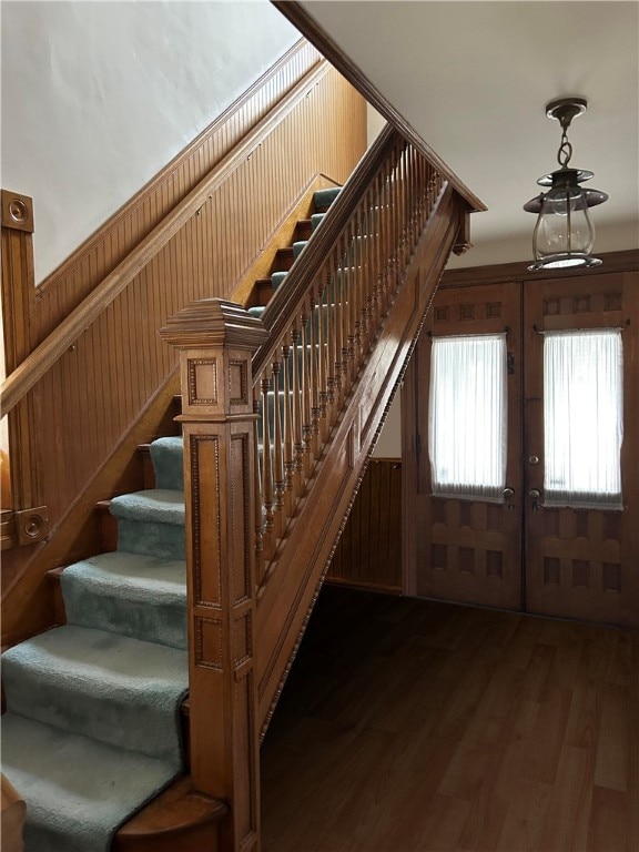 staircase featuring hardwood / wood-style floors, french doors, and wood walls