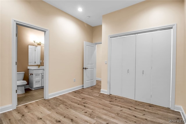 unfurnished bedroom featuring connected bathroom, a closet, light wood-type flooring, and sink