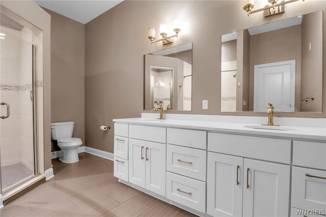 bathroom featuring double sink, a shower with shower door, toilet, and large vanity