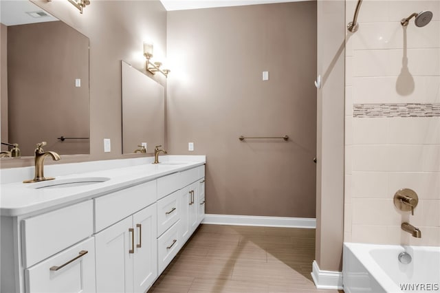 bathroom featuring double sink vanity and tiled shower / bath