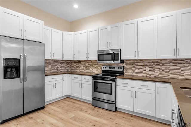 kitchen featuring light hardwood / wood-style floors, tasteful backsplash, white cabinetry, and stainless steel appliances