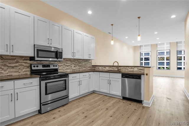 kitchen featuring backsplash, kitchen peninsula, appliances with stainless steel finishes, and light hardwood / wood-style flooring