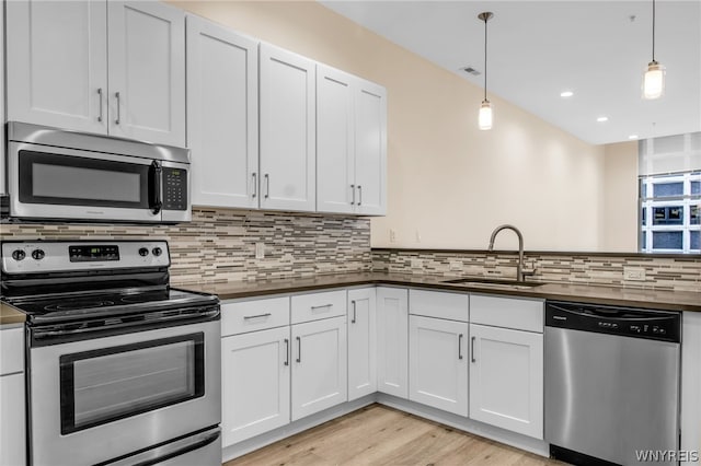 kitchen with decorative light fixtures, stainless steel appliances, sink, tasteful backsplash, and light hardwood / wood-style floors