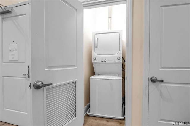 clothes washing area featuring light hardwood / wood-style floors and stacked washer and dryer