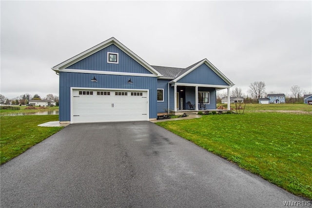 view of front of house featuring covered porch, a garage, and a front yard