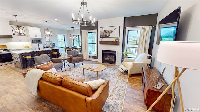 living room with wood-type flooring, a fireplace, and a notable chandelier