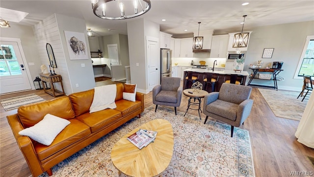 living room with light hardwood / wood-style floors and ceiling fan with notable chandelier