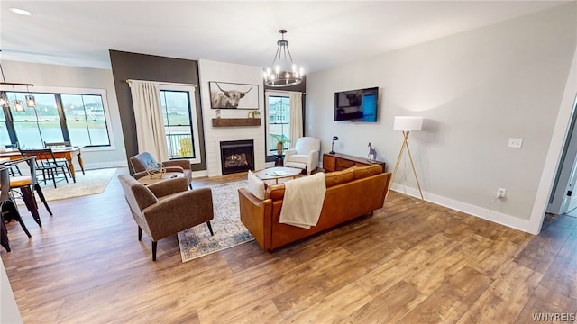 living room with a chandelier, hardwood / wood-style flooring, and a fireplace