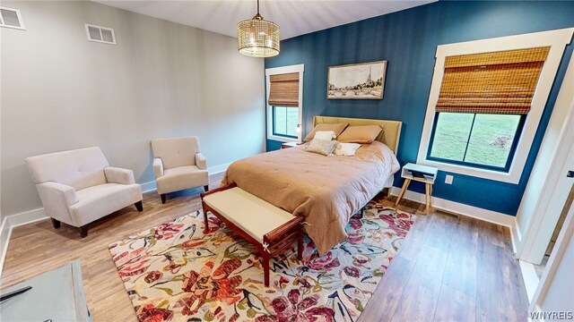 bedroom featuring hardwood / wood-style floors, multiple windows, and an inviting chandelier