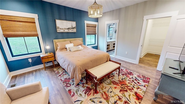 bedroom with ensuite bath, wood-type flooring, and a notable chandelier