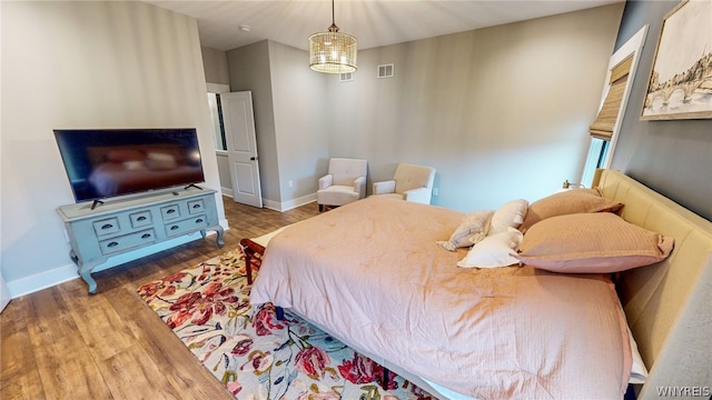 bedroom with an inviting chandelier and dark hardwood / wood-style flooring