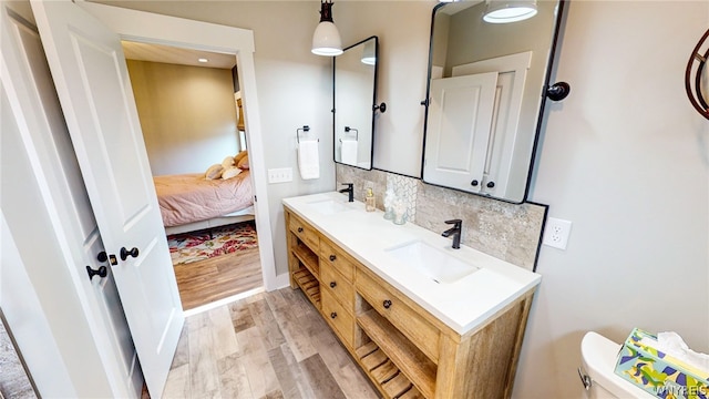 bathroom featuring oversized vanity, tasteful backsplash, double sink, toilet, and wood-type flooring