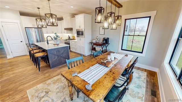 dining area with a chandelier, light hardwood / wood-style flooring, and sink