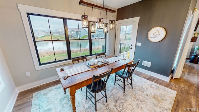 dining room featuring wood-type flooring and a water view