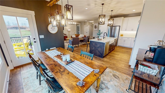 dining room with an inviting chandelier, sink, and light wood-type flooring