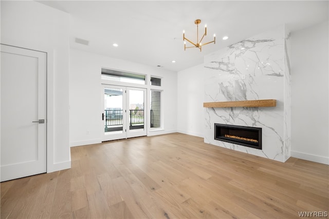 unfurnished living room featuring a chandelier, a high end fireplace, and hardwood / wood-style floors