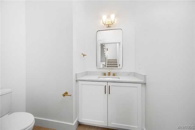 bathroom with hardwood / wood-style floors, vanity, and toilet