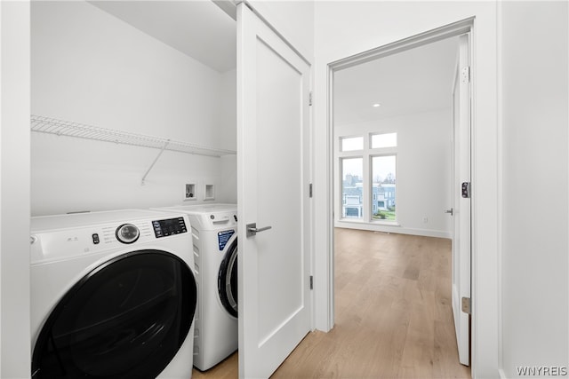 clothes washing area with hookup for a washing machine, light hardwood / wood-style flooring, and separate washer and dryer