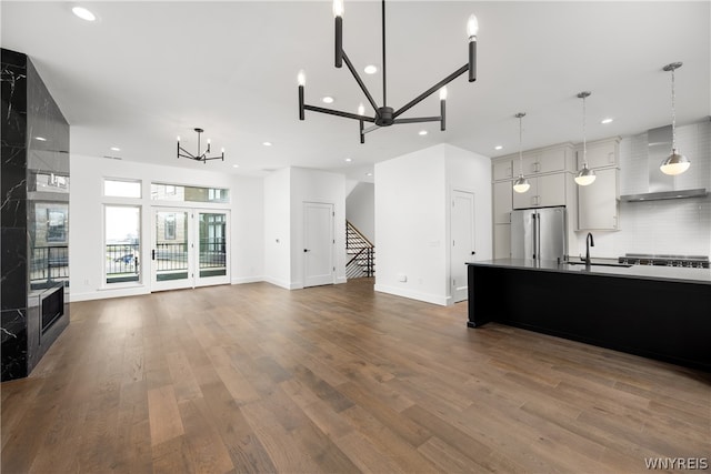 kitchen with hardwood / wood-style floors, hanging light fixtures, wall chimney range hood, and stainless steel appliances