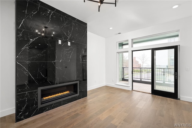 unfurnished living room featuring hardwood / wood-style flooring, a wealth of natural light, and a tiled fireplace