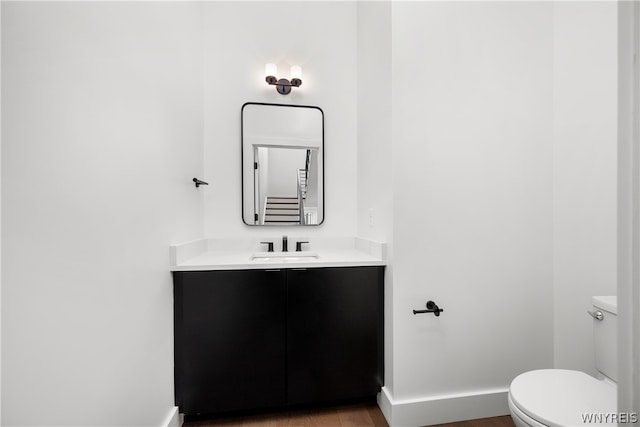 bathroom featuring hardwood / wood-style flooring, toilet, and vanity