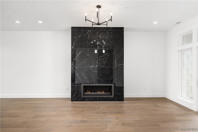 details featuring hardwood / wood-style flooring, a premium fireplace, and a chandelier