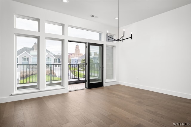 spare room featuring dark hardwood / wood-style flooring and a notable chandelier