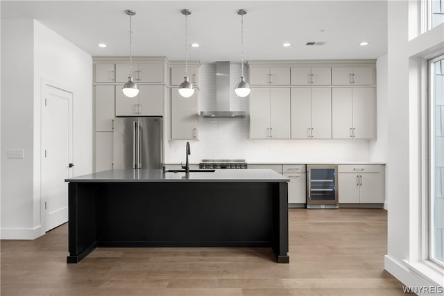 kitchen with wall chimney exhaust hood, wine cooler, light wood-type flooring, stainless steel refrigerator, and backsplash