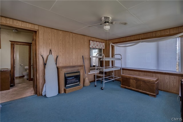 carpeted office space featuring ceiling fan and wood walls