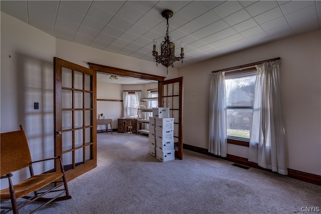 carpeted spare room with an inviting chandelier