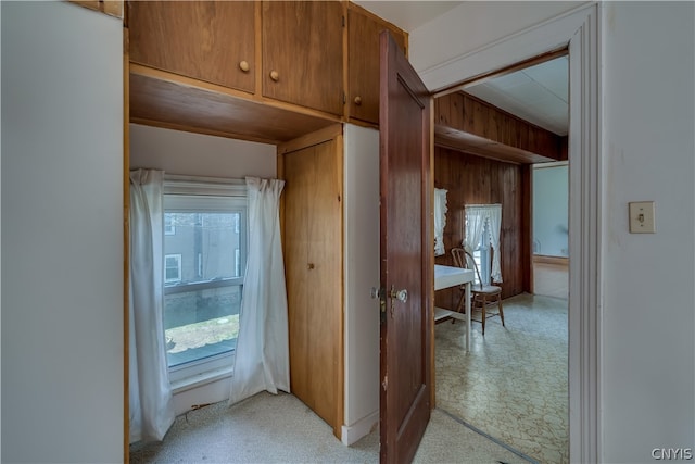 hallway with light carpet and wooden walls