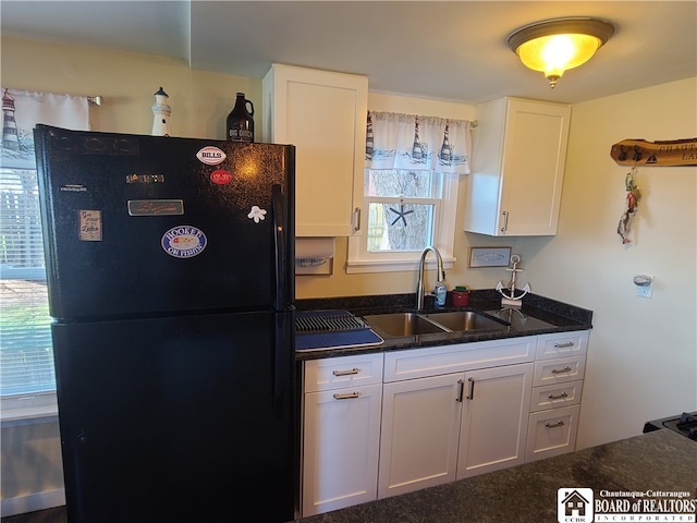 kitchen with carpet, white cabinets, black fridge, and sink