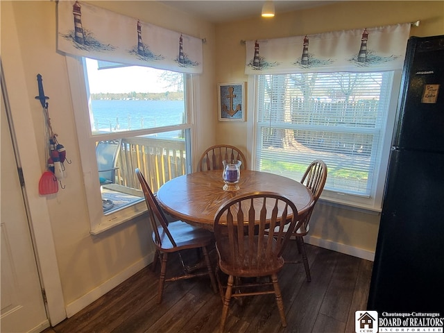 dining space with a water view, a wealth of natural light, and dark wood-type flooring