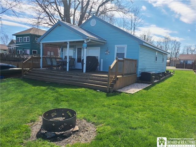 rear view of house featuring a yard, an outdoor fire pit, and a wooden deck