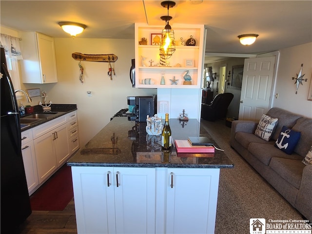 kitchen with a kitchen island, white cabinets, sink, black fridge, and dark hardwood / wood-style floors