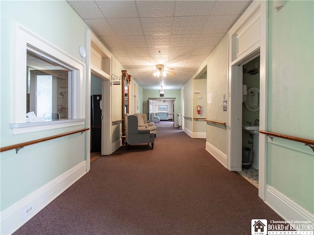 hallway featuring dark colored carpet and sink