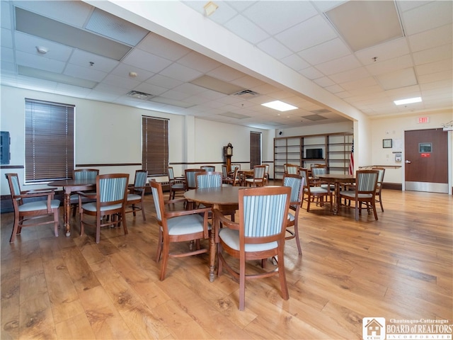 dining space with a paneled ceiling and light wood-type flooring