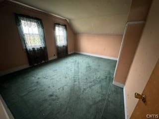 bonus room featuring lofted ceiling and dark carpet