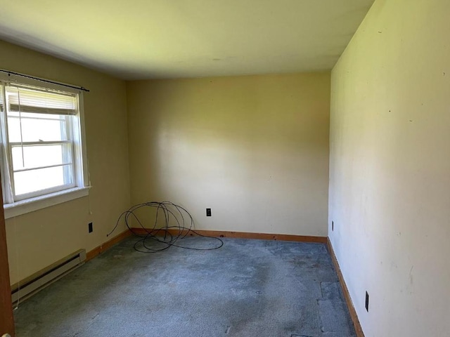 carpeted spare room with a baseboard heating unit